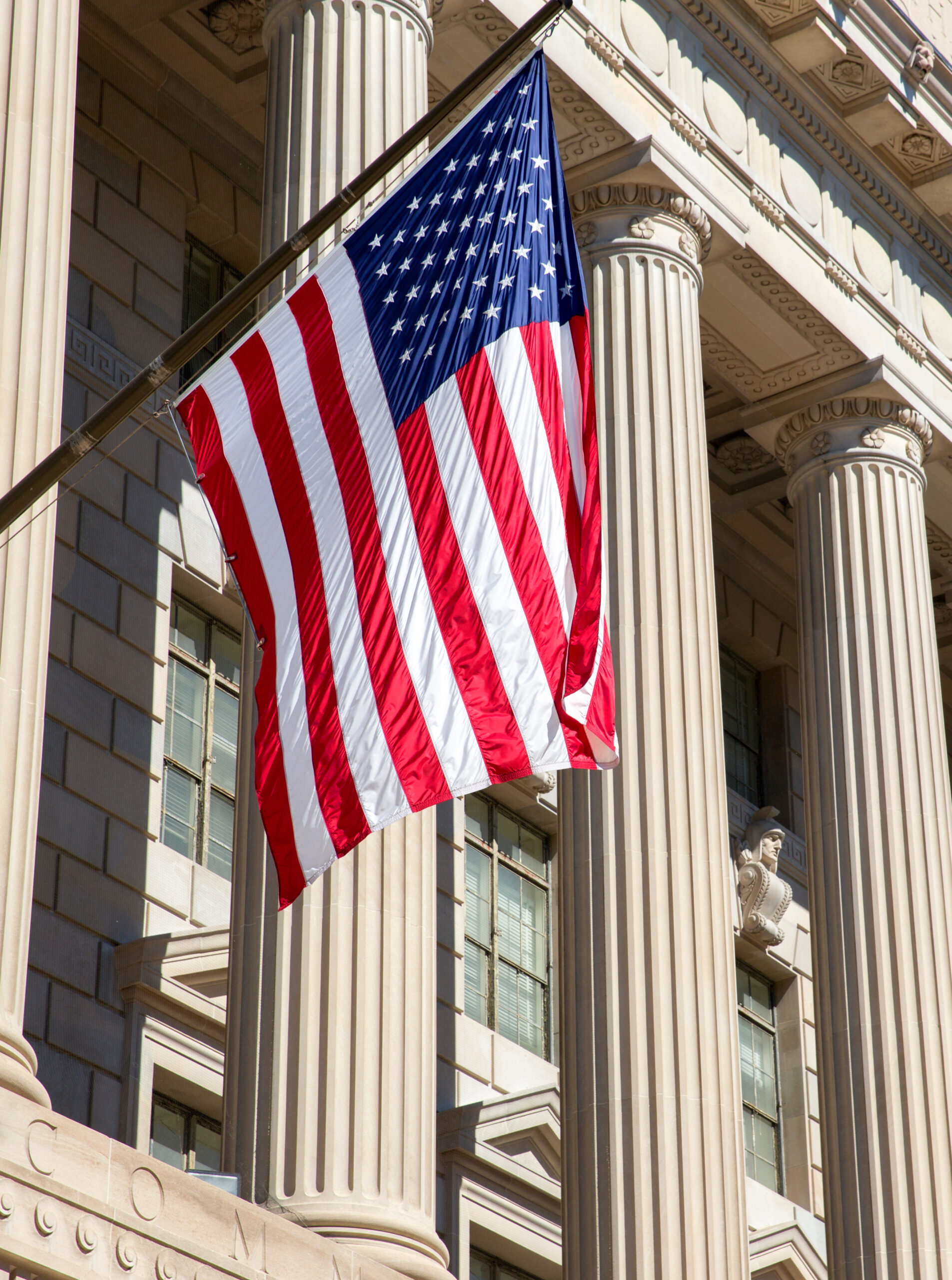 The American flag hanging outside a government building.
